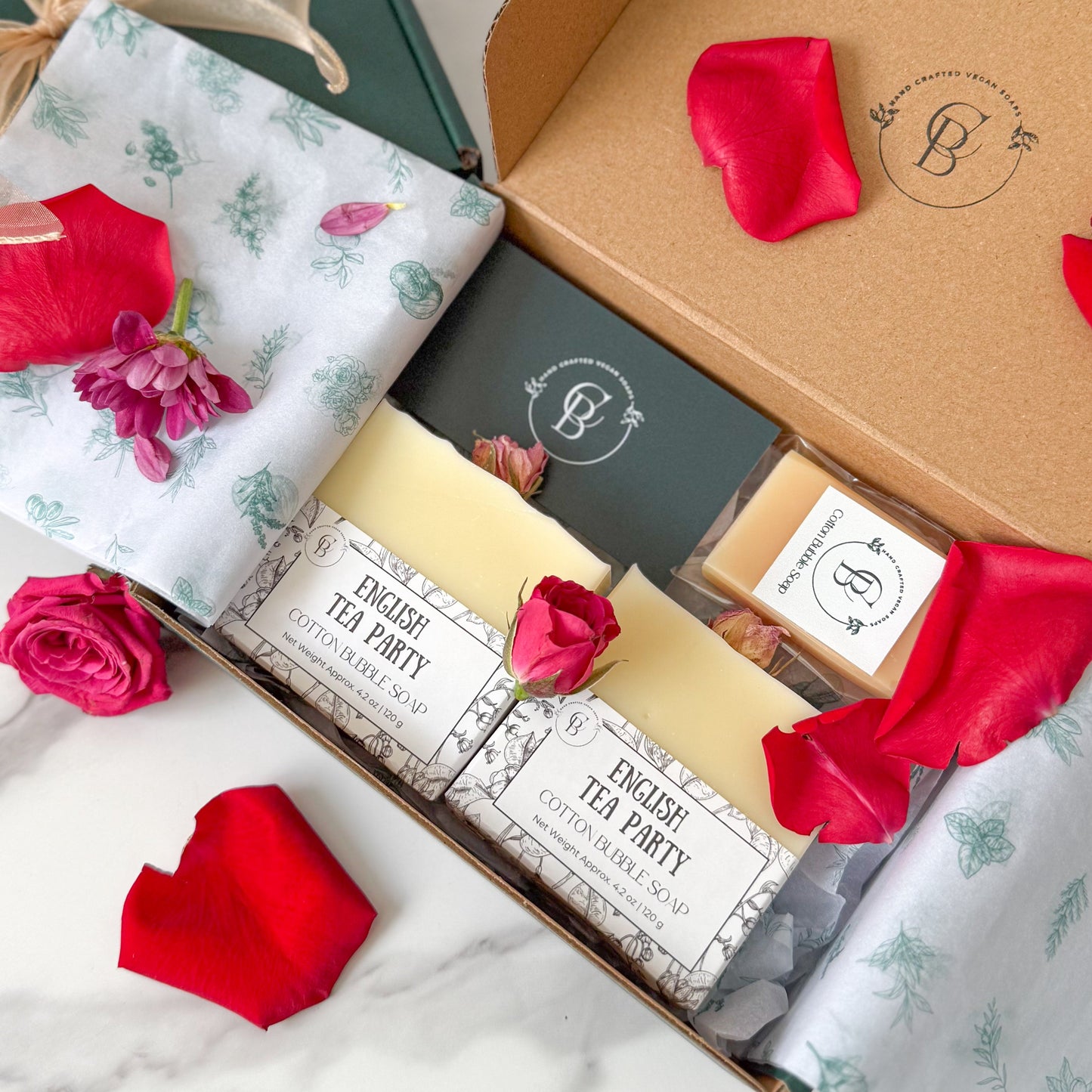 Open gift box with decorative ribbons and a card on a marble surface.