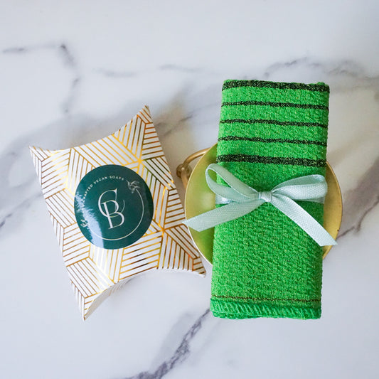 Green bath towel with a white bow on a marble surface, next to a decorative box.
