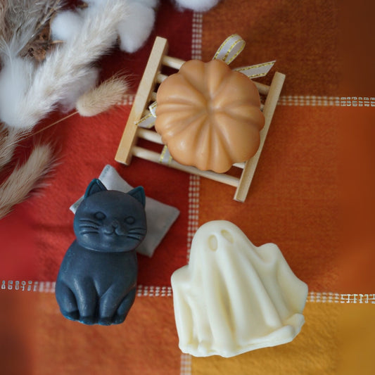 3 soaps look like a cat, a pumpkin, and a ghost onon an orange checkered fabric background
