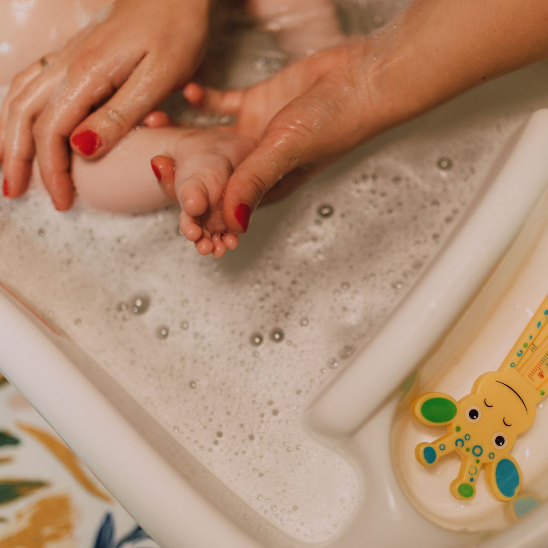 bath tub with a baby foot being washed by two hands