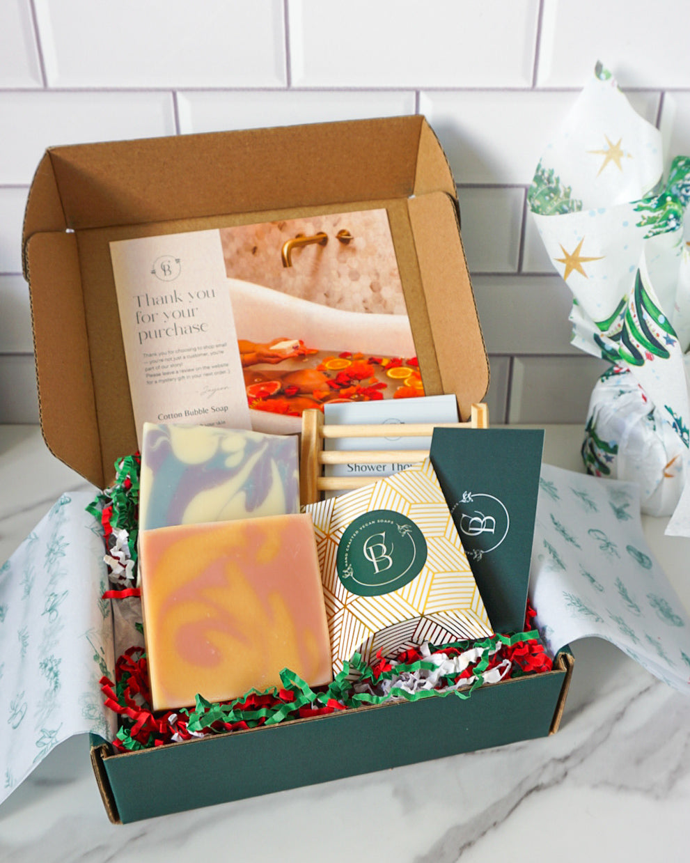 Gift box with bath products and a card on a white surface