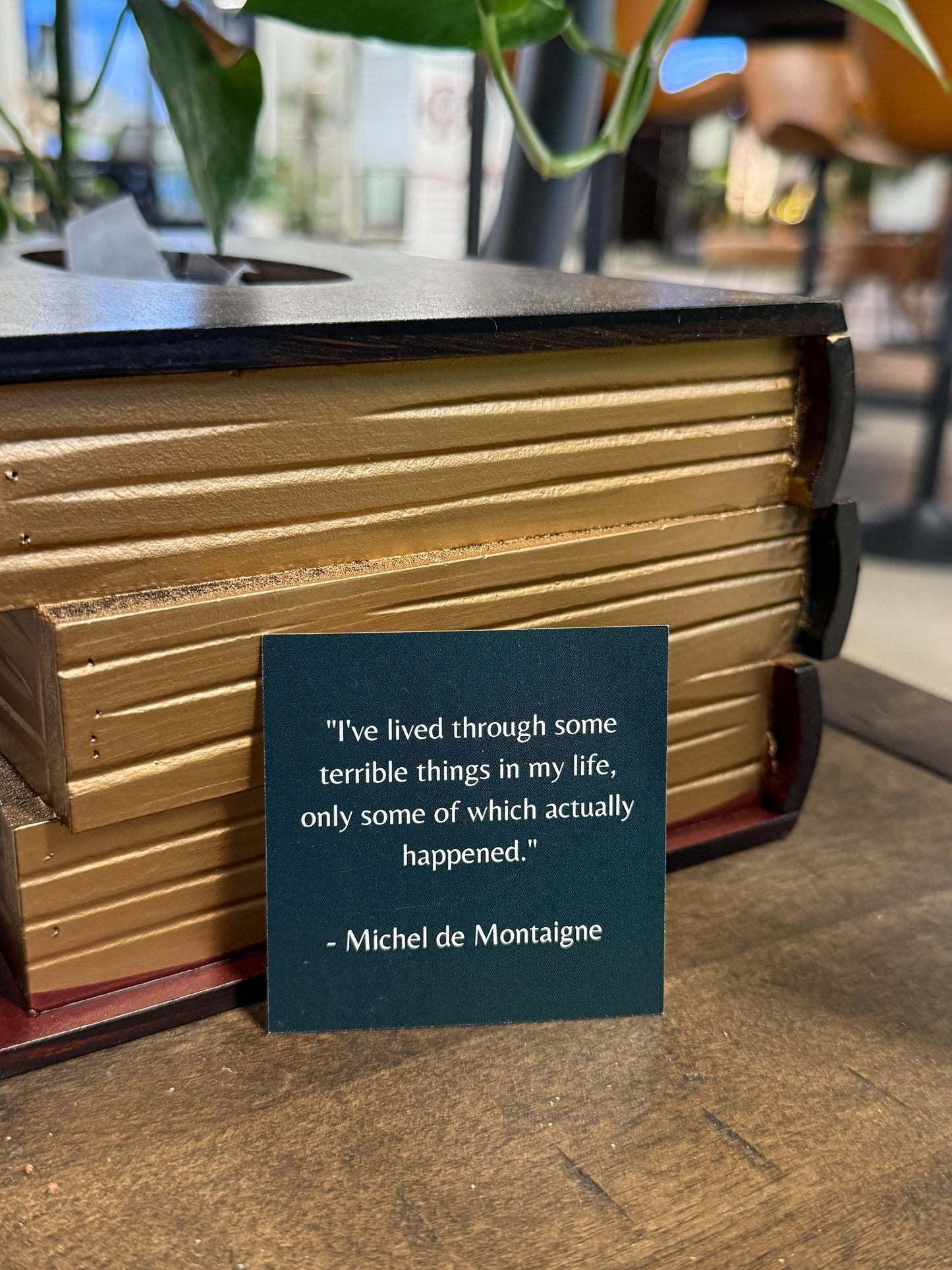 Wooden book with a quote by Michel de Montaigne on a wooden surface.