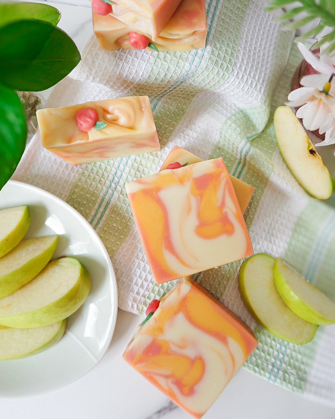 Colorful soap bars with apple slices on a white surface