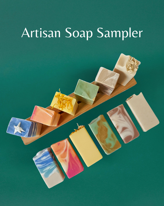 Artisan soap sampler with various colored bars on a wooden board against a green background.
