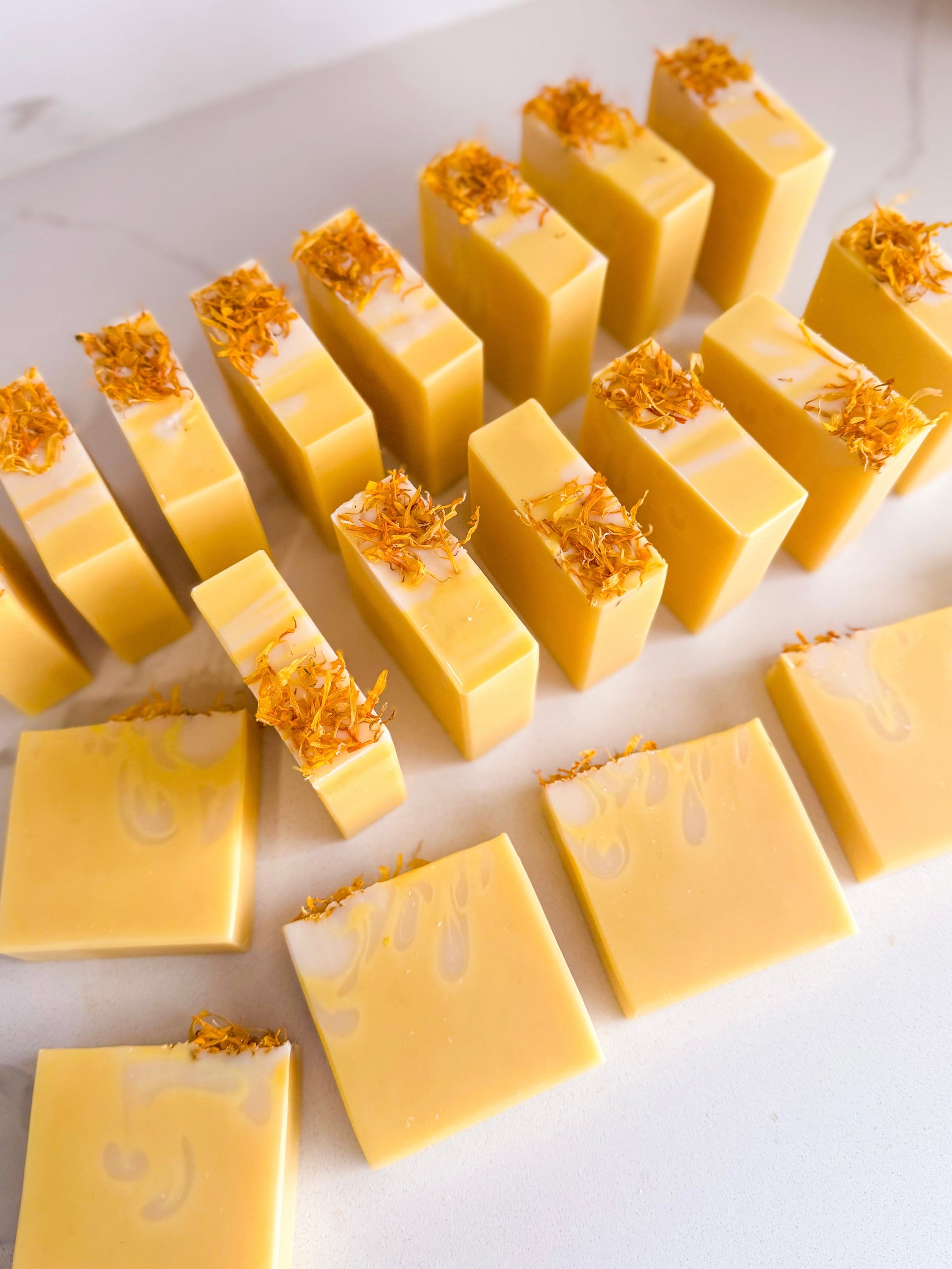 Yellow soap bars with gold flakes on a white surface
