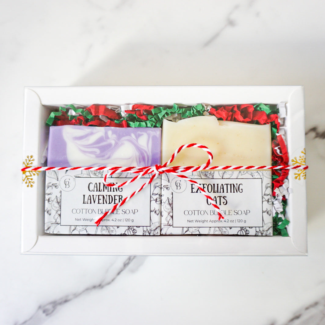 Two bars of soap in a decorative box with gift wrap on a marble surface