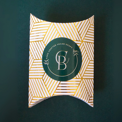 Pillow-shaped packaging with geometric pattern and brand logo on a dark green background
