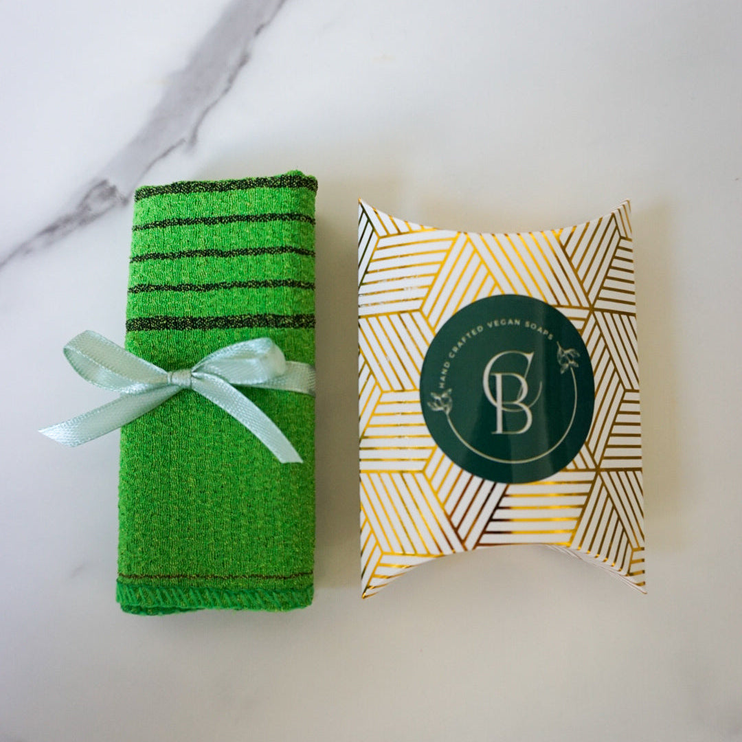 Green bath towel with a decorative box on a marble surface