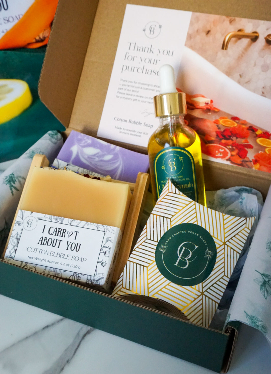 Gourmet gift box with soap, bath towel in the packaging, and bottle of oil on a marble surface