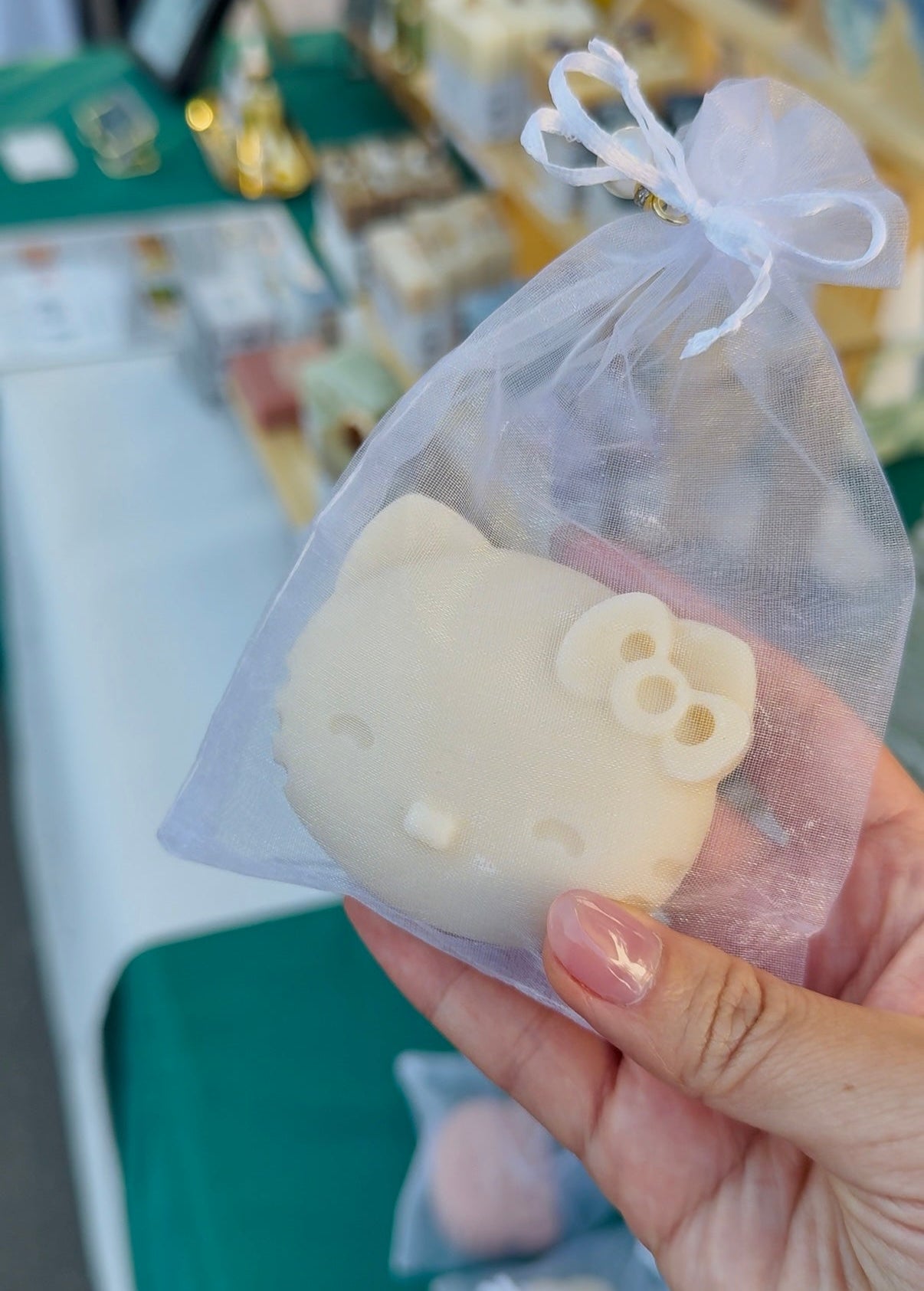 Hand holding a hello kitty shaped soap in a white pouch