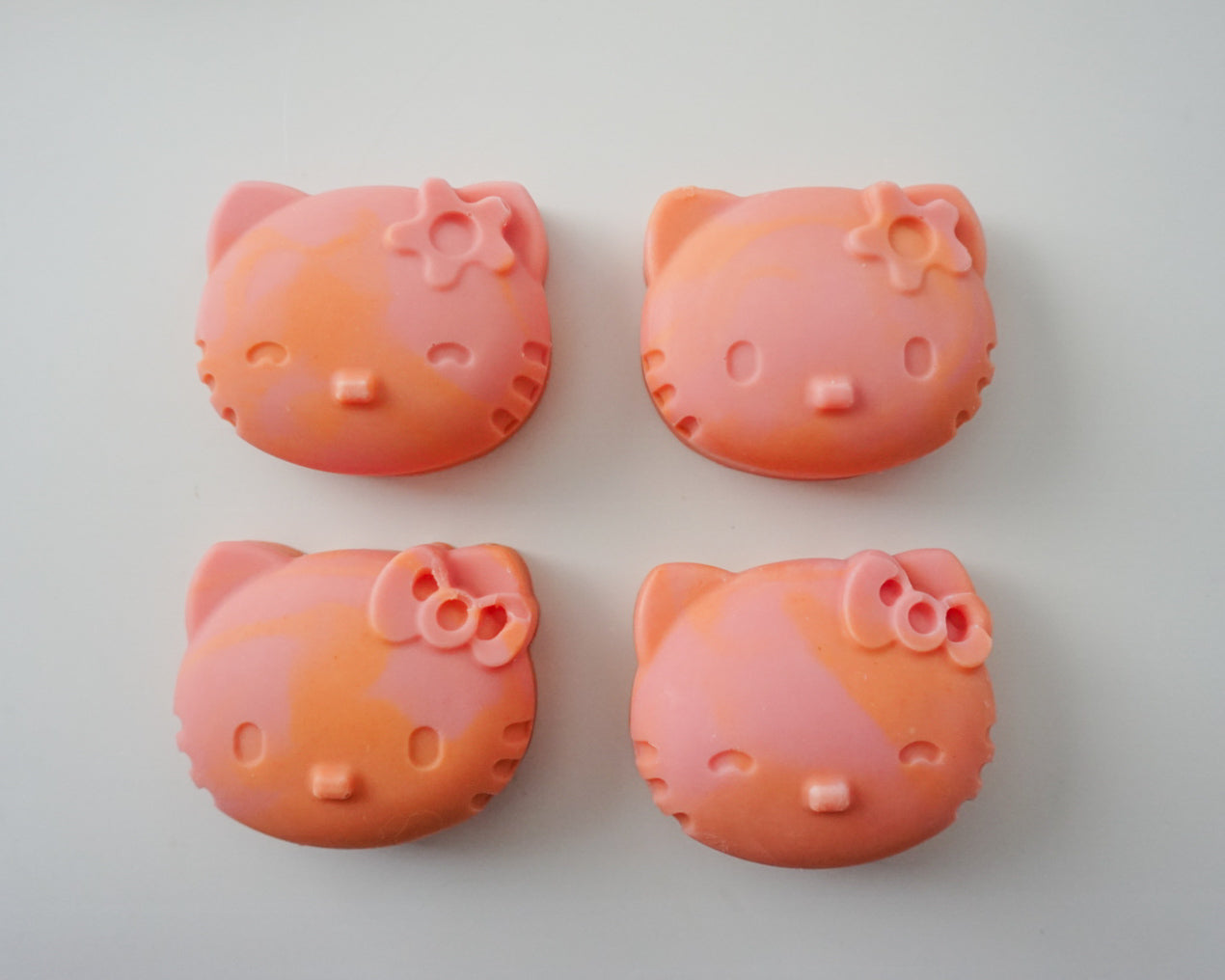 Four pink Hello Kitty Soaps with facial features on a white background