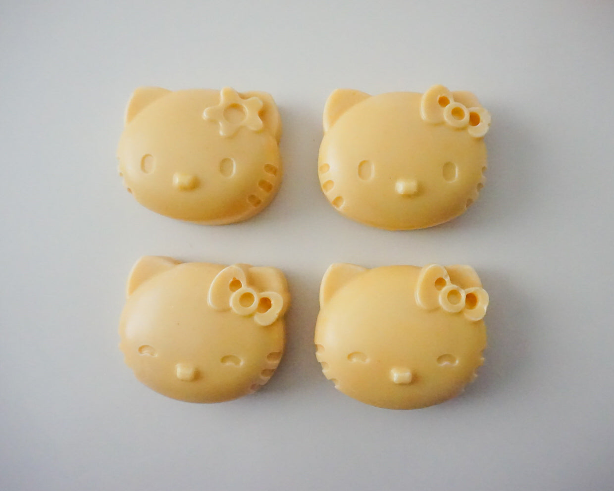 Four yellow Hello Kitty Soaps with facial features on a white background