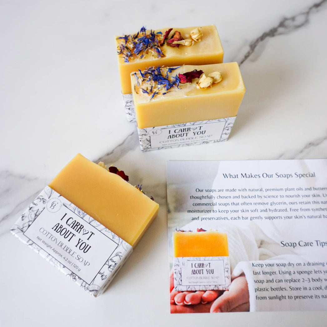 Three handmade soap bars with decorative elements on a marble surface.