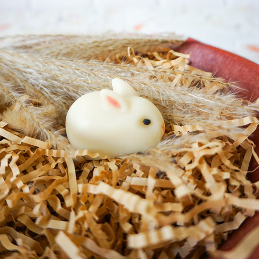 White rabbit-shaped soap on a bed of straw with a white background