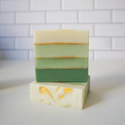 Stack of layered soap bars on a white surface with a tiled wall background