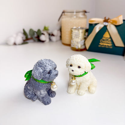 Two small dog figurine soaps with green ribbons on a white surface.