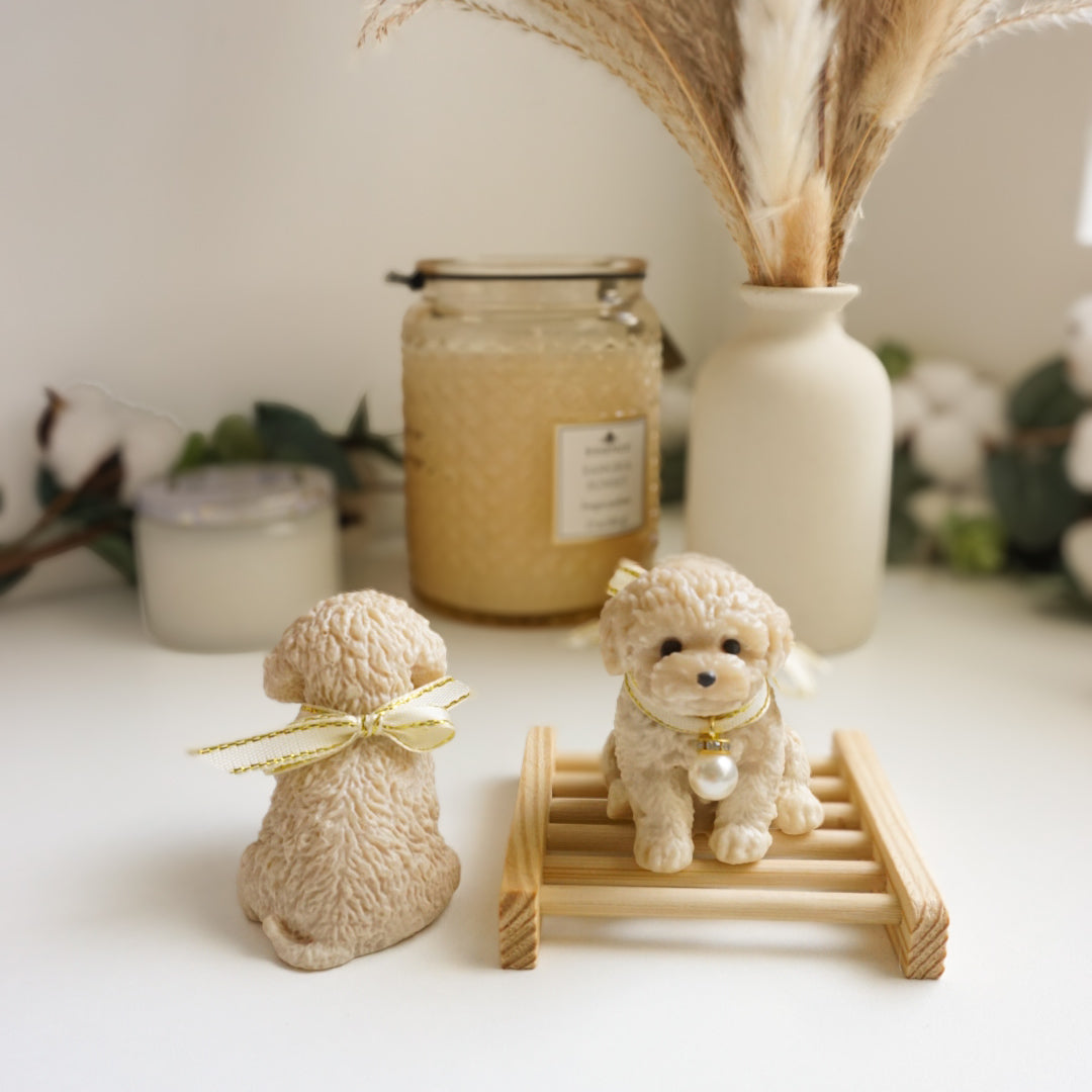 Two small dog figurine soaps  on a white surface with decorative elements in the background.