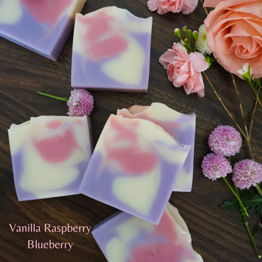 Vanilla Raspberry Blueberry soap bars with pink flowers on a wooden surface