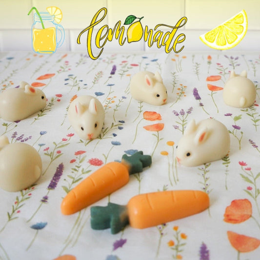 Small animal figurines that are actually bunnies with carrots also soap on a floral-patterned background, featuring the scent profile Lemonade